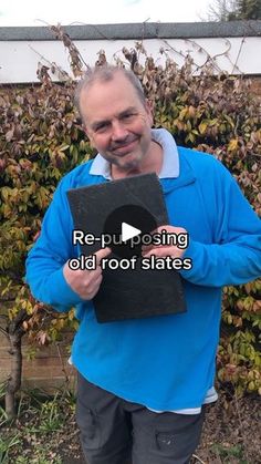 a man holding up a black plaque in front of a bush with words reading repurposing old rot states