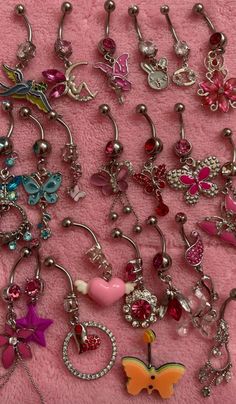 many different types of dangling belly rings on a pink blanket with beads and charms attached to them