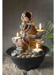 a water fountain with rocks and candles in it