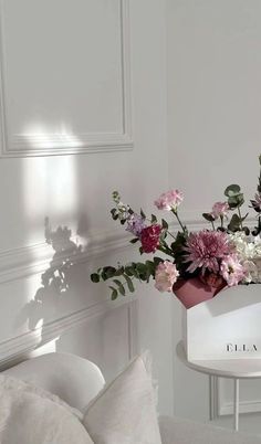 a vase filled with pink and white flowers on top of a table next to a chair