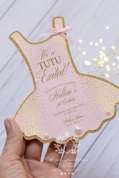 a hand holding up a pink and gold dress shaped card