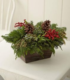 two pine cones are sitting on top of a planter filled with greenery and berries