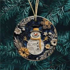 a snowman ornament hanging on a christmas tree with blue and gold ornaments