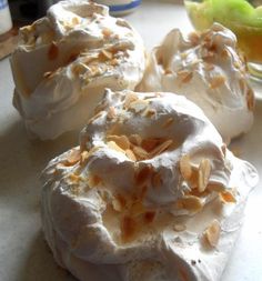 three meringue covered donuts sitting on a counter top next to an apple