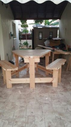 a wooden table and benches sitting in a room with tile flooring on the ground