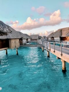 the water is very blue and clear with some huts on each side that are connected by wooden poles