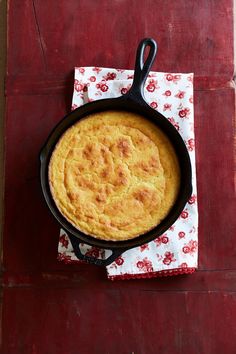 a skillet with some food in it on a red table cloth next to a fork