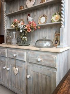 an old china cabinet with flowers and plates on it