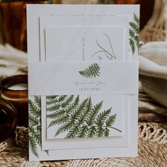 two cards with green leaves on them sitting next to a candle and some other items