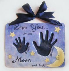 a ceramic plaque with two hands and the words love you to the moon and back