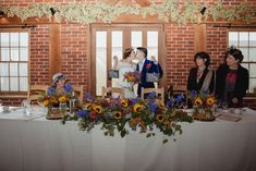 a bride and groom kiss at the end of their wedding reception table with sunflowers