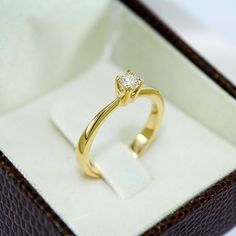 a yellow gold ring with a diamond in it's box on a white surface