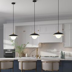 three lights hanging over a kitchen island with stools next to it and a potted plant on the counter