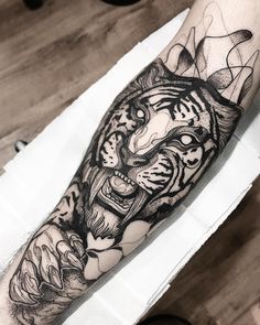 a black and white tiger tattoo on the left arm, with an abstract design behind it