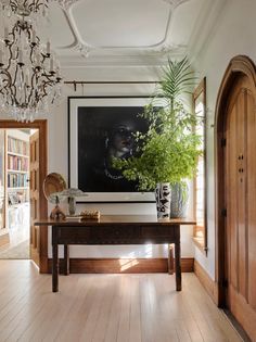 an entryway with a table, potted plant and chandelier