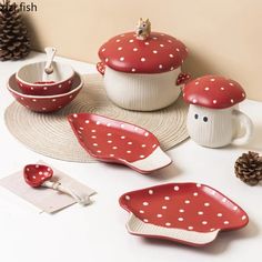 red and white dishes with polka dots on them are sitting on a place mat next to pine cones