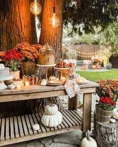 an outdoor table with candles, pumpkins and other decorations on it in front of a tree