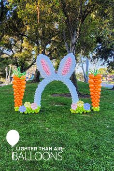 an inflatable balloon bunny with carrots on the grass and trees behind it that says, lighter than air balloons