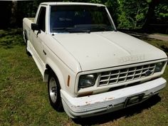 an old white pick up truck parked in the grass