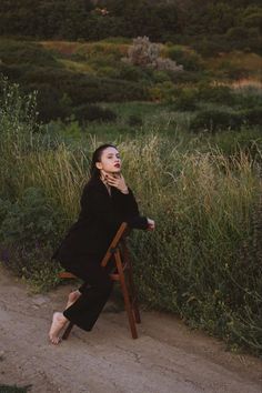 a woman sitting in a chair on the side of a road talking on a cell phone