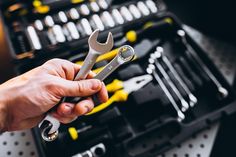 a man holding a wrench in his hand with other tools inside the toolbox