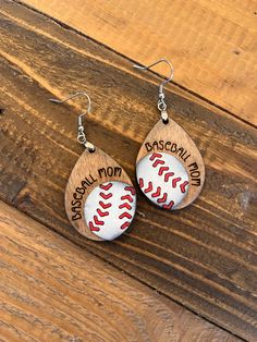 two baseball earrings with the words baseball mom and dad on them sitting on a wooden surface