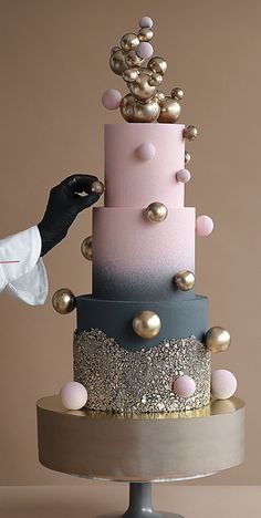 a woman is decorating a multi - tiered cake with gold and pink decorations