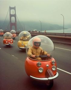 three people in small cars driving down the road with a bridge in the back ground