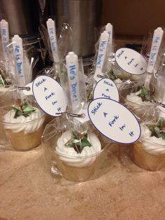 cupcakes wrapped in plastic wrappers with holly decorations