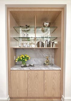 a wooden cabinet with glass shelves and flowers in the vases on top of it