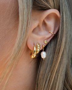 a close up of a person wearing gold ear clips with pearls on the end of them