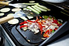 the food is being cooked on the grill with tongs and spatula in it