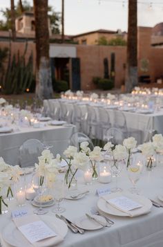 the tables are set with white flowers and place settings