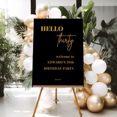 a black and gold birthday party sign on a tripod with balloons in the background