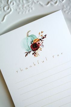 a thank card with an image of a blue pumpkin and flowers on it, sitting next to a lace doily