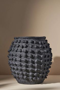 a black vase sitting on top of a table next to a brown wall and floor