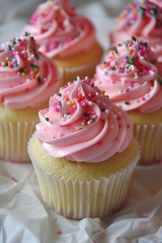 cupcakes with pink frosting and sprinkles on white paper towel