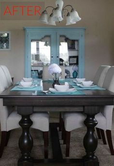 a dining room table with white chairs and blue china cabinet in the backround