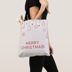 a woman carrying a white christmas bag with red writing on the front and silver handles