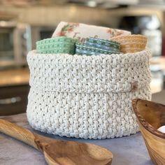 a crocheted basket sitting on top of a counter next to a wooden spoon