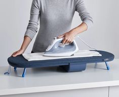 a woman ironing clothes with an electric iron