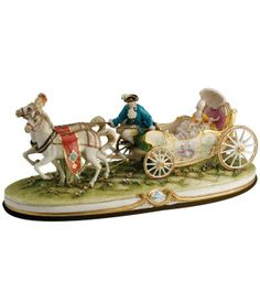 a figurine of a man driving a horse drawn carriage with two women in it