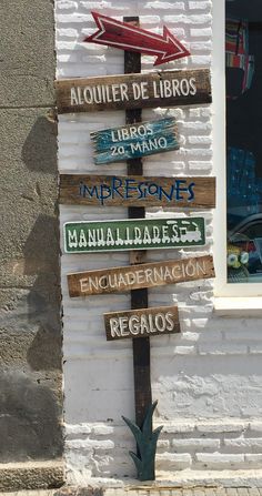 a wooden sign with many different signs on it in front of a white brick building