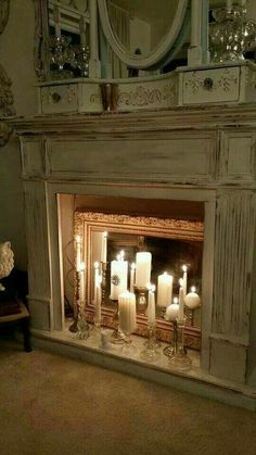 a fireplace with candles lit in front of it and a mirror on the wall above