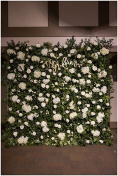 white flowers and greenery are arranged in the shape of a wall for a wedding reception