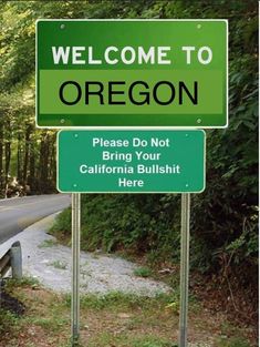 a welcome to oregon sign is posted on the side of a road in front of some trees