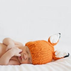 a baby sleeping with a knitted fox hat on