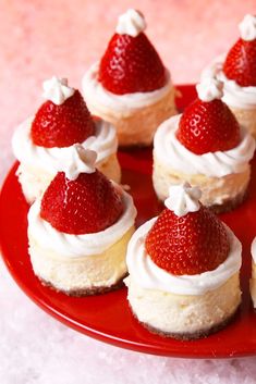 small strawberry cheesecakes on a red plate with whipped cream and fresh strawberries