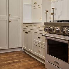 a kitchen with white cabinets and stainless steel stove top oven in the center of the room