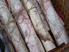 several maps wrapped in twine on top of each other next to a wicker basket